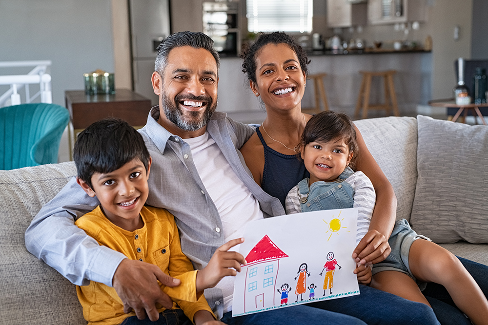 Smiling Black mother and Middle Eastern father with two children showing handmade painting of family.