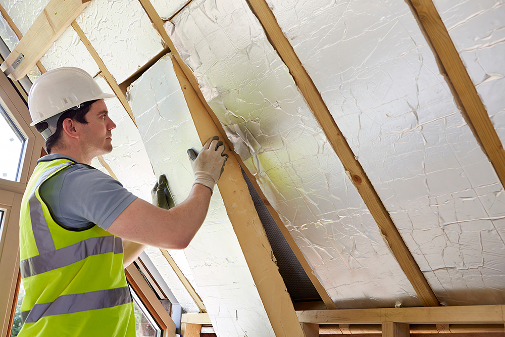 Builder Fitting Insulation Into Roof Of  Home
